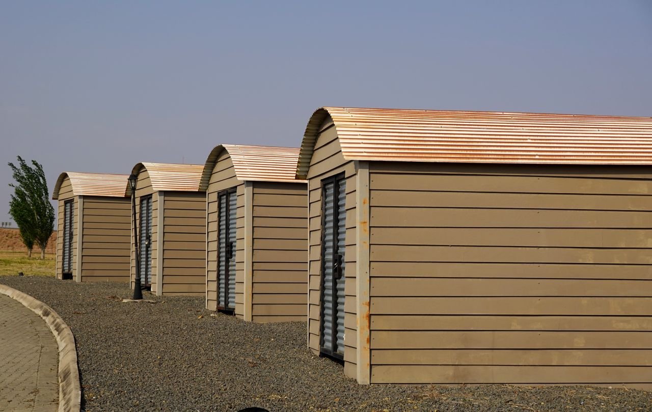 Crafting Captivating Headlines: Your awesome post title goes here Four identical modern storage sheds aligned on a gravel surface with clear skies.