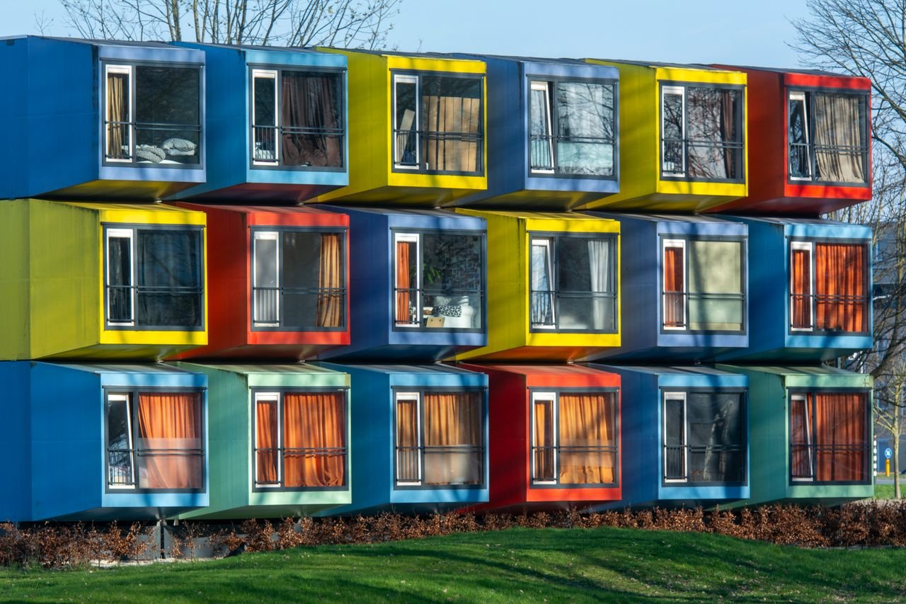 Services-01 Vibrant exterior of colorful modular housing units with varied window designs.